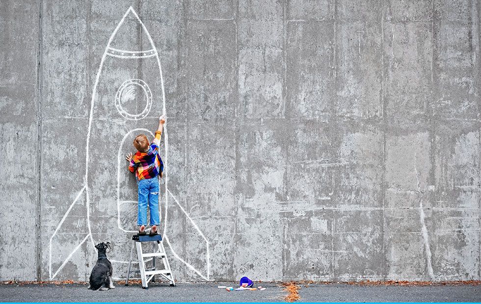 primary school boy drawing rocket on wall