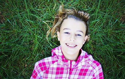 happy smiling girl lying on grass 